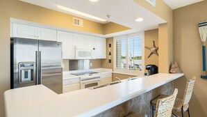 A modern kitchen with white cabinets, stainless steel appliances, and a large island with bar stools.