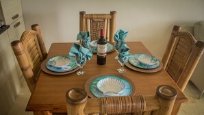 Un tavolo da pranzo in legno con una bottiglia di vino, due piatti e due bicchieri.