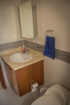 Een badkamer met een wastafel, spiegel, handdoekrek en toilet.