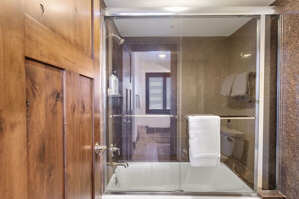 Un baño moderno con ducha de vidrio, bañera blanca y muebles de madera.