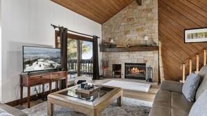 A cozy living room with a stone fireplace, a television, and a comfortable sofa.