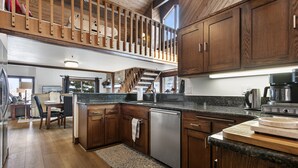 A spacious kitchen with wooden cabinets, a stainless steel dishwasher, and a granite countertop.