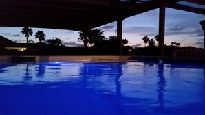Une piscine avec vue sur les palmiers et sur le coucher de soleil.
