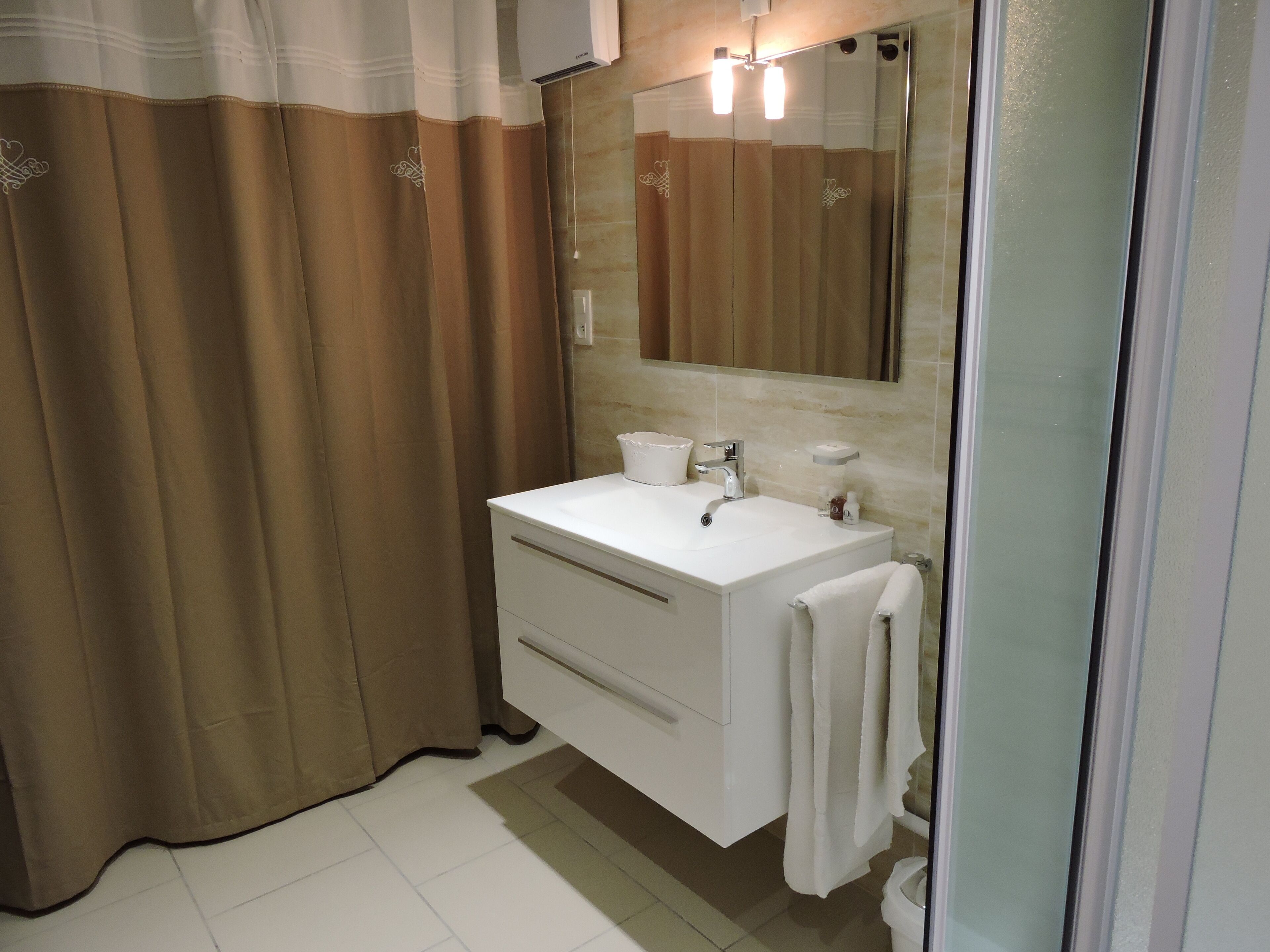 A bathroom with a white sink, mirror, and towel hanging on the wall.