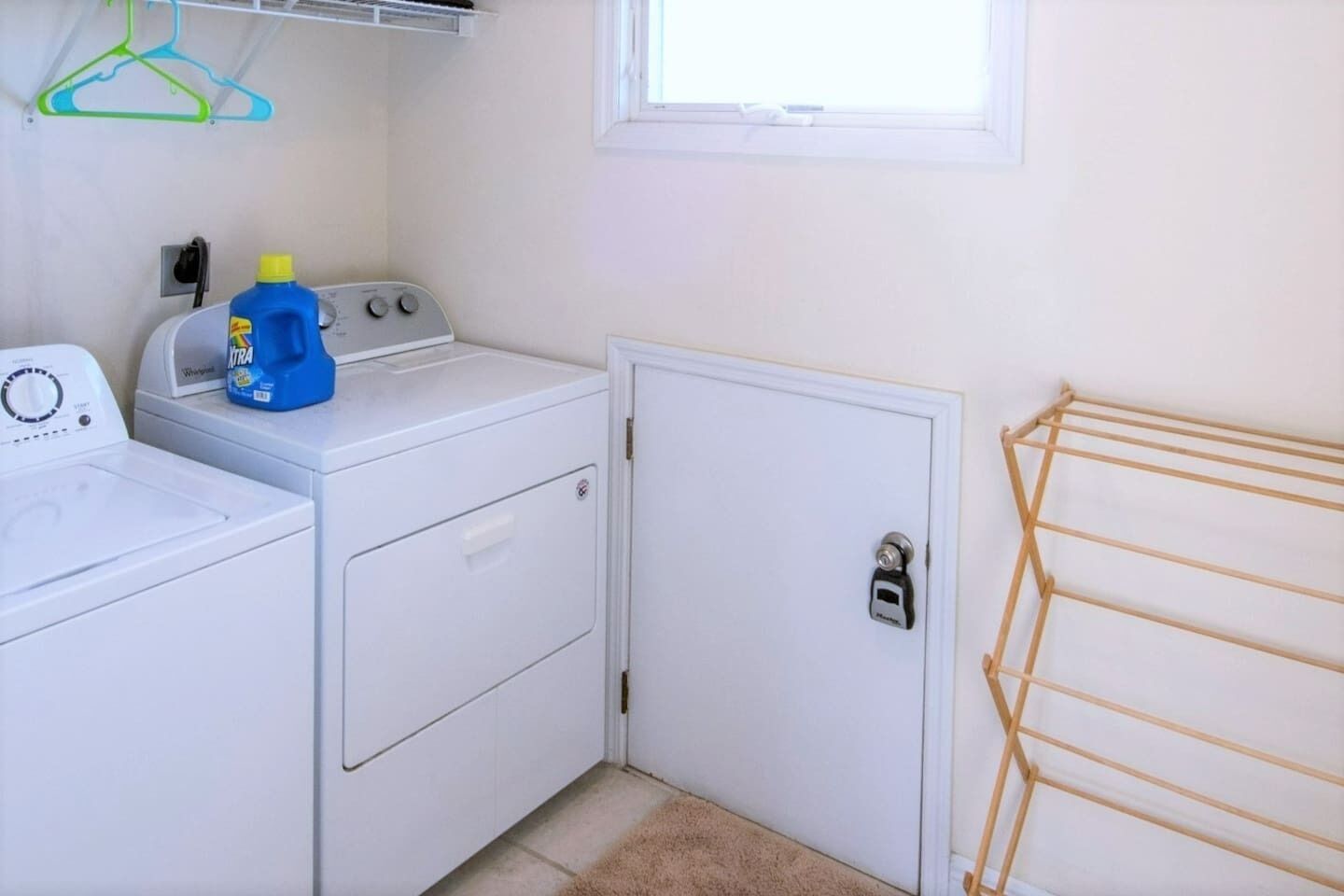 A laundry room with a washing machine, dryer, and a drying rack.