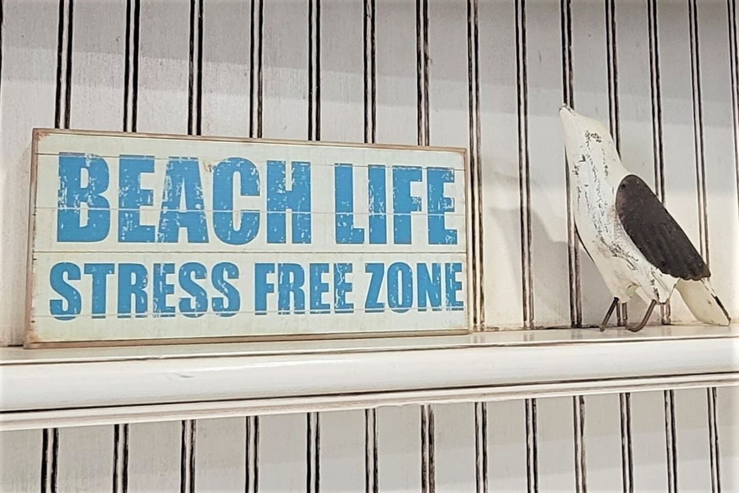 Une affiche sur fond blanc, ornée de lignes verticales, portant l'inscription « ZONE DÉDIÉE À LA DÉTENTE SUR LA PLAGE ».