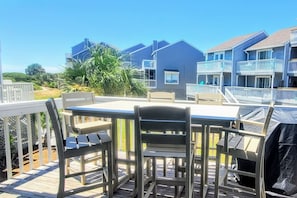 Una terraza con mesa y sillas, con vistas a una zona residencial con casas y un cielo despejado.