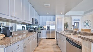 Una cocina moderna con encimeras de granito, electrodomésticos de acero inoxidable y armarios en color gris claro.