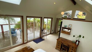 Une chambre spacieuse avec un grand lit, un bureau en bois et une vue sur un balcon aménagé avec du mobilier d’extérieur.