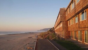 Een strandhotel met een modern ontwerp, met een lange gang met grote ramen en een pad dat naar het strand leidt.