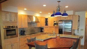 Una cocina moderna con armarios de madera, electrodomésticos de acero inoxidable y una isla central con taburetes de bar.