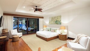 A modern hotel room with a bed, a sitting area with a chair and a table, a ceiling fan, and a large window with a view. - Beautiful sunset ocean views, two pools, great for families, private beach club, personal concierge (Papagayo Peninsula)