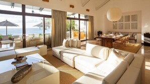A spacious living room with a large sofa, a coffee table, and a dining area with a table and chairs. - Beautiful sunset ocean views, two pools, great for families, private beach club, personal concierge (Papagayo Peninsula)