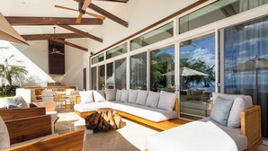 A modern living room with a sofa, wooden coffee table, and a dining area with chairs and a table. - Beautiful sunset ocean views, two pools, great for families, private beach club, personal concierge (Papagayo Peninsula)