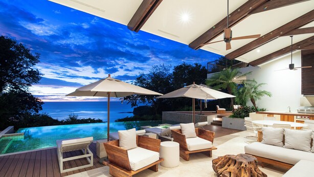 An outdoor deck with wooden furniture, a wooden coffee table, and umbrellas. - Beautiful sunset ocean views, two pools, great for families, private beach club, personal concierge (Papagayo Peninsula)