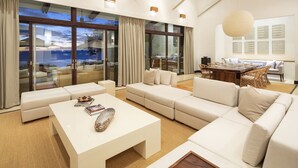A spacious living room with a large sectional sofa, a white coffee table, and a dining area with wicker chairs. - Beautiful sunset ocean views, two pools, great for families, private beach club, personal concierge (Papagayo Peninsula)