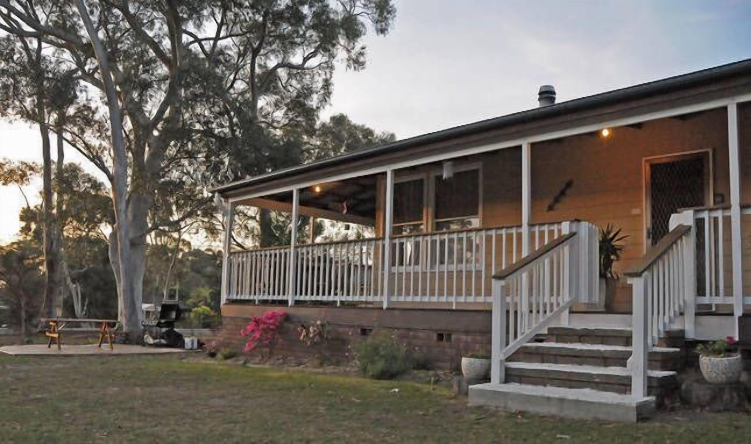 Ein zweistöckiges Haus mit einer Veranda, einer Treppe und einem Rasen.