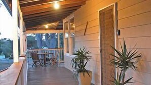 Un espace extérieur abrité doté d’une terrasse en bois, de plantes en pot et d’un coin salon avec des chaises.