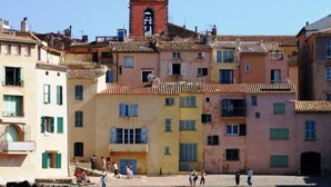 A coastal town with colorful buildings, a prominent yellow tower, and a clear blue sky. - La Bastide, apartment with private pool near the Gulf of St Tropez (Fréjus)