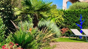 A garden with various plants, a pathway, and a blue sculpture. - La Bastide, apartment with private pool near the Gulf of St Tropez (Fréjus)
