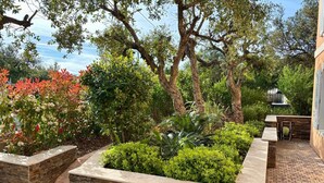 A landscaped garden with stone planters, a brick patio, and various shrubs and trees. - La Bastide, apartment with private pool near the Gulf of St Tropez (Fréjus)
