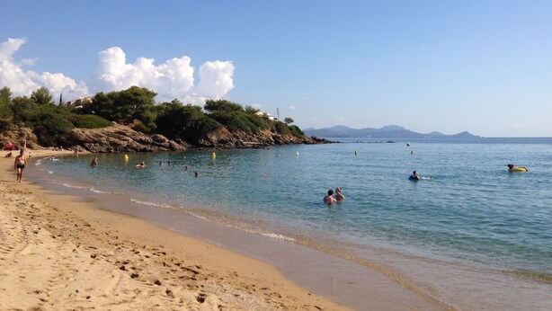 A beach with clear water, people swimming and walking along the shore, and a rocky outcrop with vegetation in the background. - La Bastide, apartment with private pool near the Gulf of St Tropez (Fréjus)