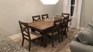 Un comedor con una mesa de madera, seis sillas, una araña y un ordenador portátil sobre la mesa.