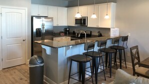 Cocina moderna con armarios blancos, electrodomésticos de acero inoxidable y encimera de granito.