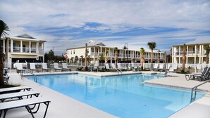 Zona de piscina con sillas de descanso y un edificio con balcones.