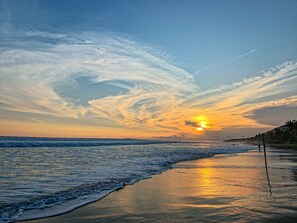 Una platja amb onades, un capvespre i un cel clar.