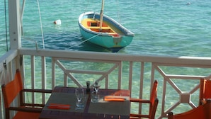 A boat docked at a pier with a table and chairs in the foreground. - Cause desistement Magnifique duplex jardin privatif, piscine et si dispo clio3 (Saint-François)