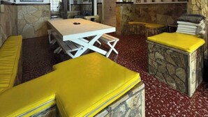 Un comedor con una mesa y bancos, paredes de piedra y obras de arte en las paredes.