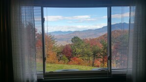 A window with a view of a mountainous landscape and autumn foliage. - Gorgeous fall colors views from  mtn top condo! King bed hot tubs sauna. Promos! (Gatlinburg)