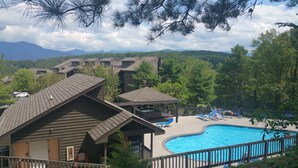 A resort with a swimming pool, lounge chairs, and a view of mountains. - Gorgeous fall colors views from  mtn top condo! King bed hot tubs sauna. Promos! (Gatlinburg)
