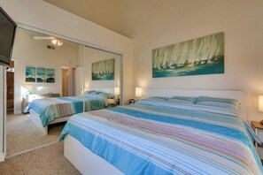 A bedroom with two beds, a large mirror, and a painting of sailboats.