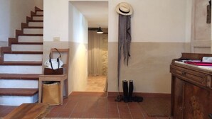 Eine Treppe führt zu einem Flur, an der Wand hängt ein Hut, ein Holzschrank steht dort, und ein Paar Stiefel ist zu sehen.