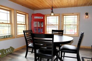 Un comedor con una mesa redonda y cuatro sillas, un teléfono rojo y un letrero que dice "LAKE".