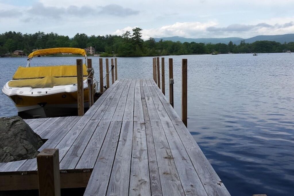 Eine Holzsteganlage, die sich in einen ruhigen See erstreckt, mit einem Boot am Ende vertäut.