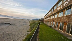 Ein Gebäude mit dem Schriftzug "SEA GYPSY" auf der Fassade, neben einem Strand mit einer Rasenfläche und einem Zaun.