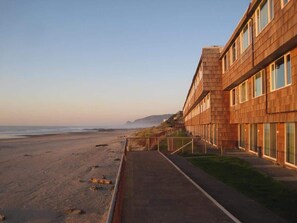 A beachfront hotel with a long, straight pathway leading to the beach, wooden exterior, and large windows. - Spacious Top Floor Oceanfront Suite - Pool and Sauna - Sleeps 4! (Lincoln City)