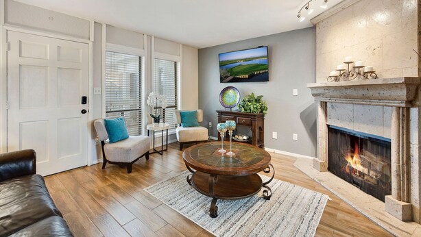 A living room with a fireplace, a round coffee table, a sofa, and a television mounted on the wall. - Pet-Friendly Old Town Scottsdale! (Scottsdale)