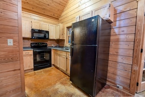 Compact kitchen with a stove, microwave, and refrigerator, perfect for basic meal preparation.