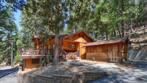 A wooden cabin with a deck, a garage, and a stone retaining wall.