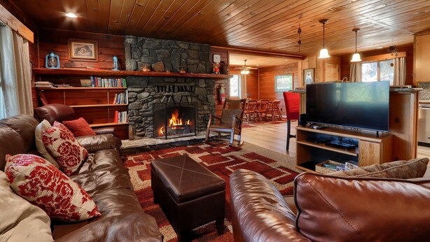A cozy living room with a stone fireplace, leather furniture, and a television.