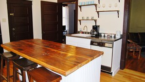 Une cuisine avec un îlot central en bois, des tabourets de bar, un lave-vaisselle et un meuble à vin.