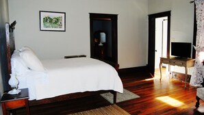 Une chambre à coucher comprenant un lit, une table de chevet, une lampe, un miroir, une commode et un téléviseur.