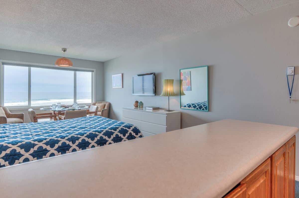 A hotel room with a bed, a desk, and a view of the ocean.