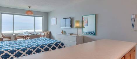 A hotel room with a bed, a desk, and a view of the ocean.