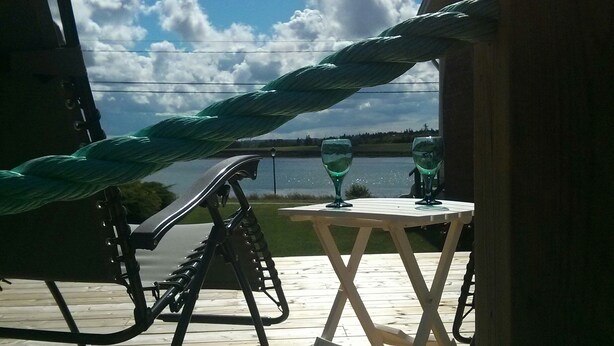 Eine Hängematte, ein Tisch und der Blick auf Himmel und Wasser.