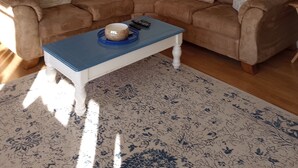 Ein Wohnzimmer mit einem braunen Ecksofa, einem blauen Couchtisch und einem dekorativen Spiegel an der Wand.